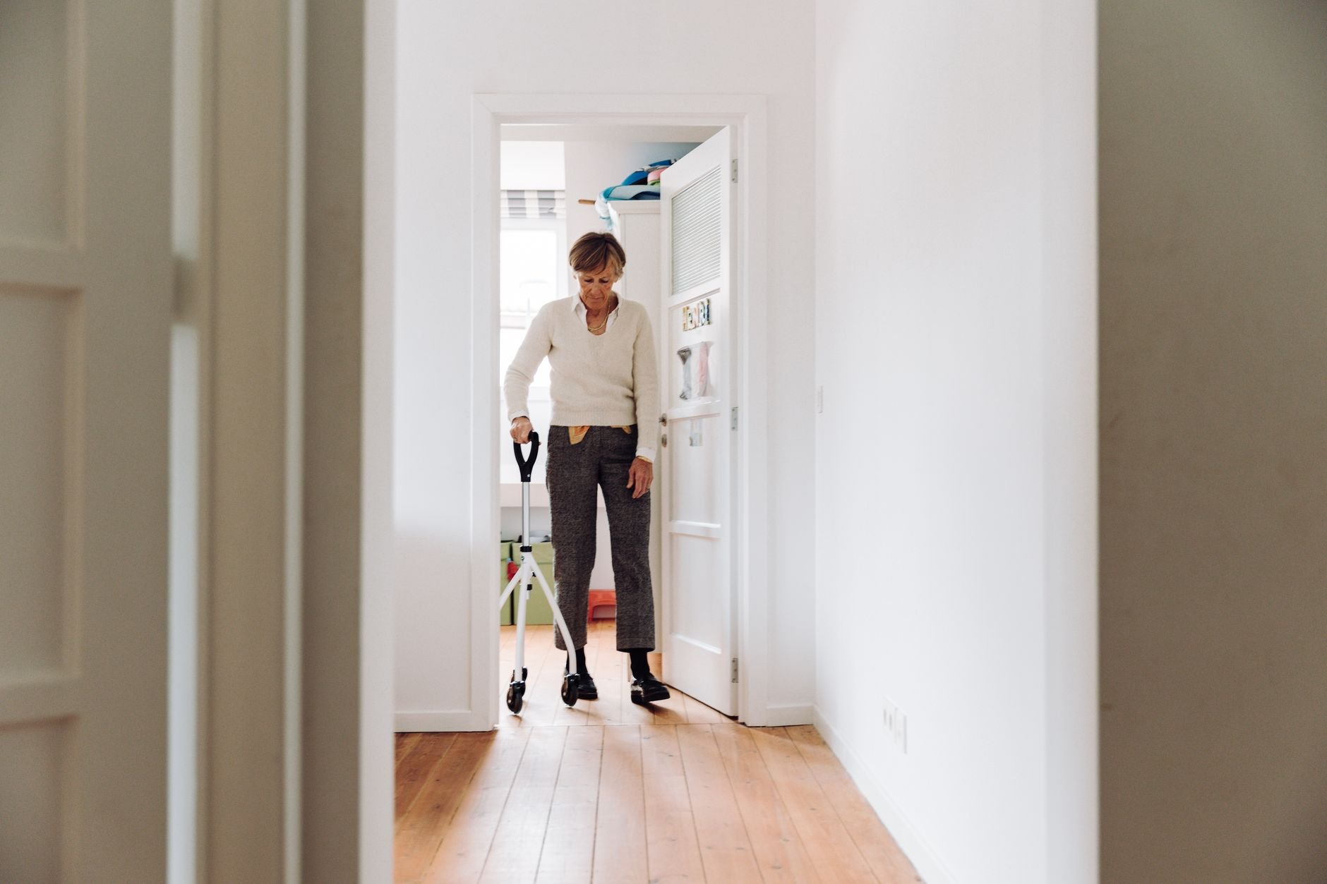 Senior woman walking confidently with a rollator in a bright home hallway