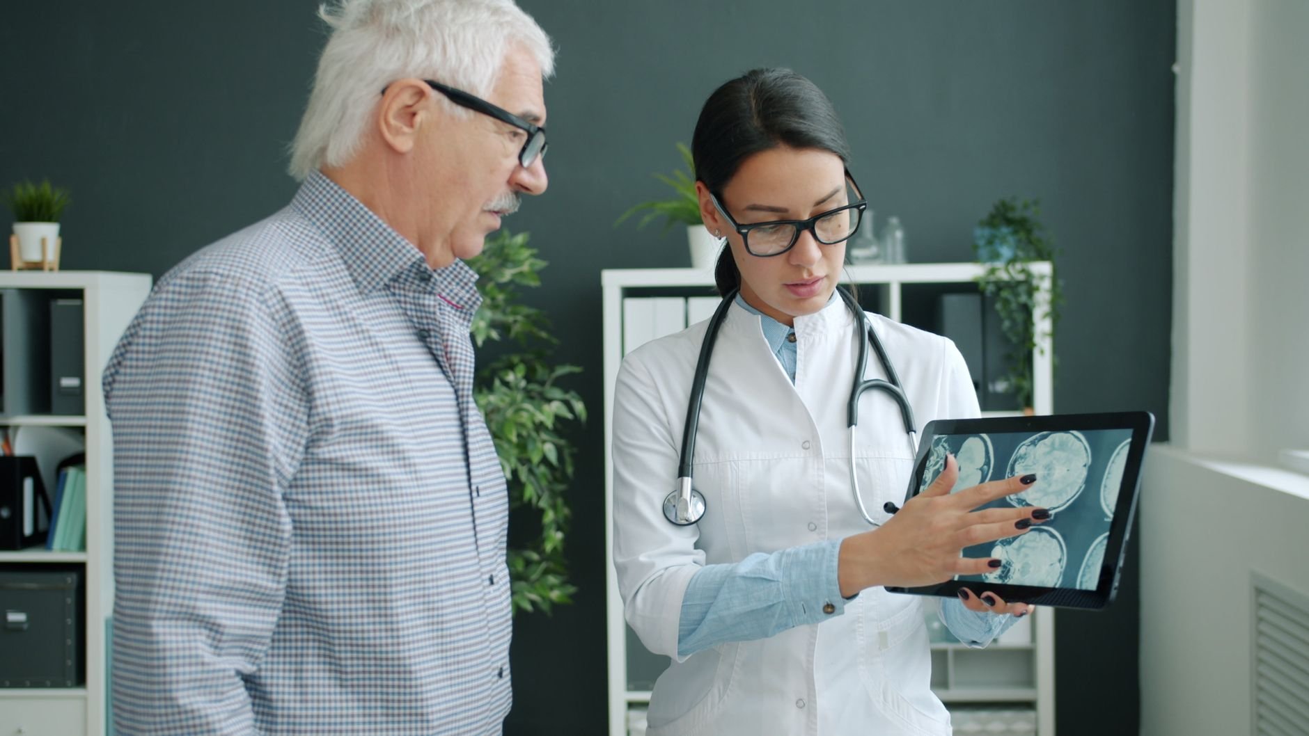Medical professional reviewing patient imaging with an elderly man in a clinic setting